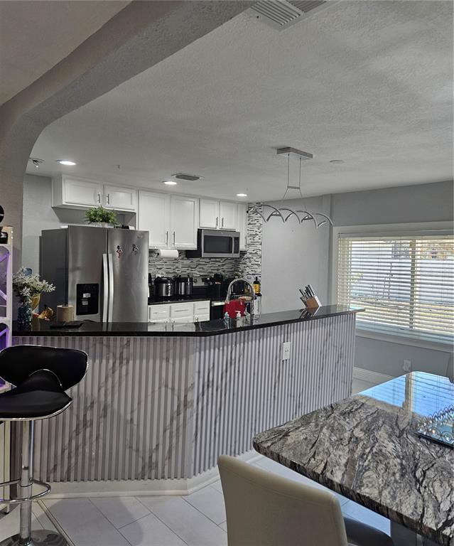 A kitchen features white cabinets, black countertops, and a marble-patterned slatted breakfast bar — 9306 FOREST HILLS DRIVE, TAMPA, FL