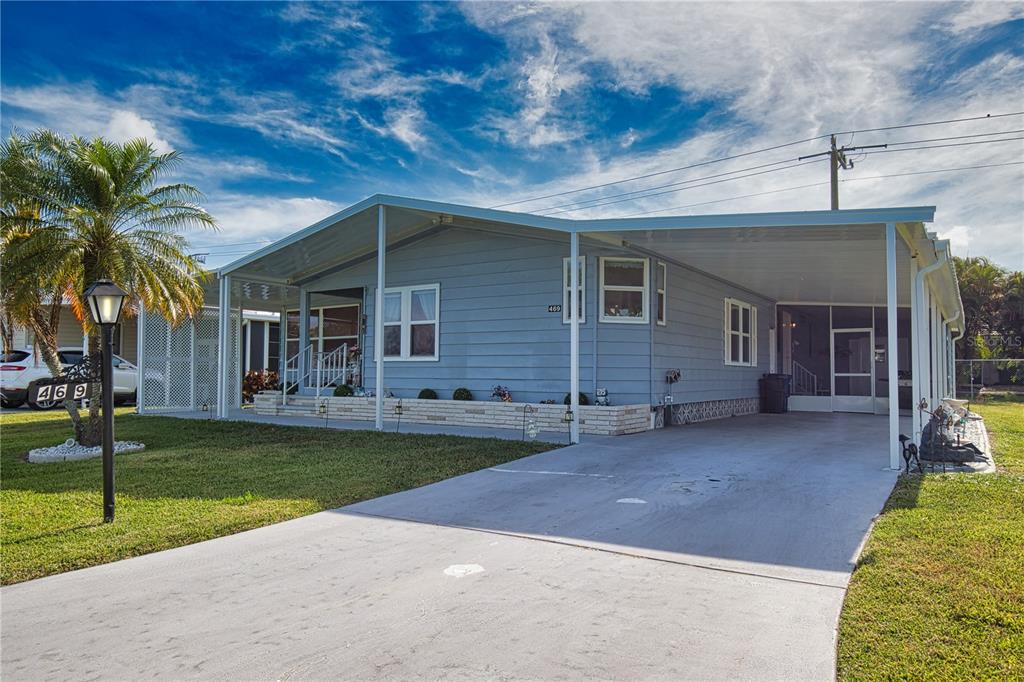 A light blue single-story manufactured home with a concrete driveway and an attached carport — 469 LOMA LINDA, NORTH PORT, FL