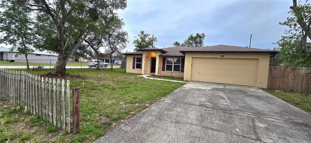 A single-story house with a beige exterior, a two-car garage, and a wooden picket fence — 2729 SWEET SPRINGS STREET, DELTONA, FL