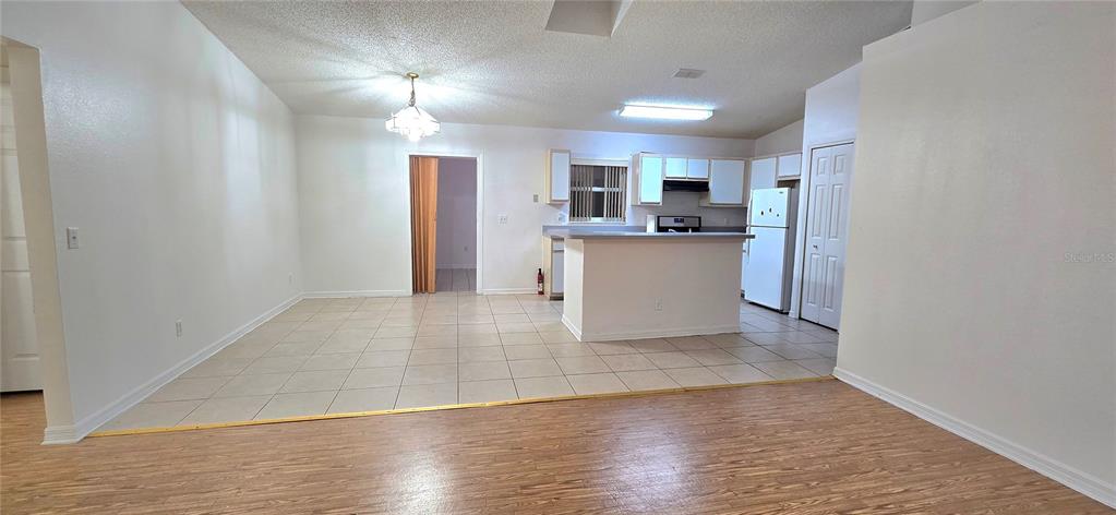 An open-concept kitchen with white cabinets and a breakfast bar overlooks a tiled dining area — 2729 SWEET SPRINGS STREET, DELTONA, FL