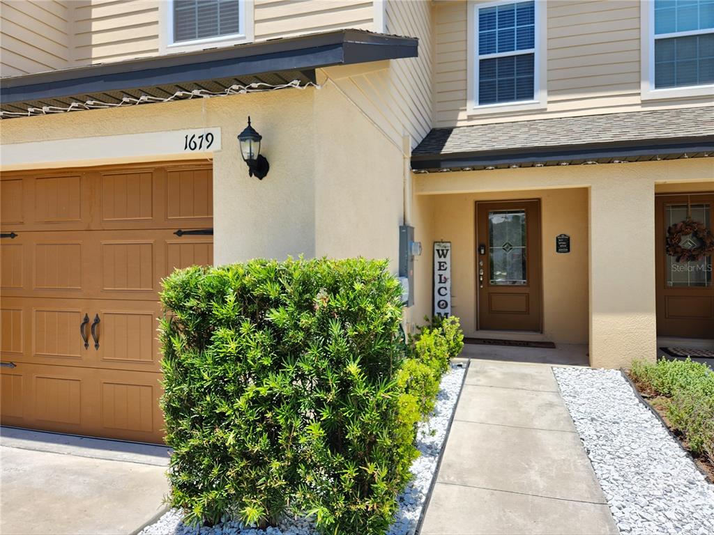 The exterior of a two-story home features a garage, a front entrance, and landscaping — 1679 WYNFORD CIRCLE, TAVARES, FL