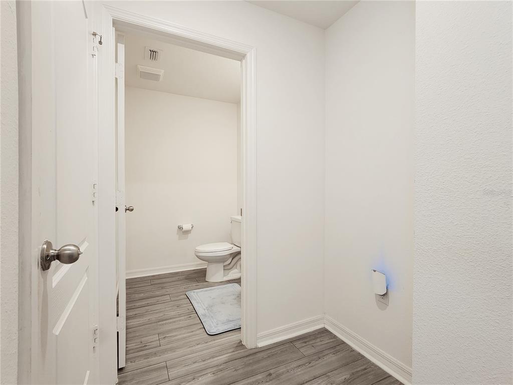 A view of a bathroom with gray wood-look flooring through an open doorway — 1679 WYNFORD CIRCLE, TAVARES, FL