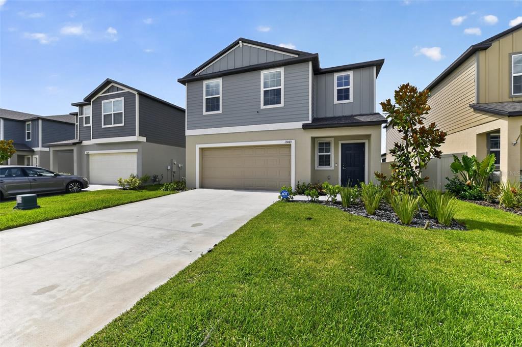 A two-story suburban house with a gray exterior, a two-car garage, and a front lawn — 13065 EMPRESS JEWEL TRAIL, PARRISH, FL