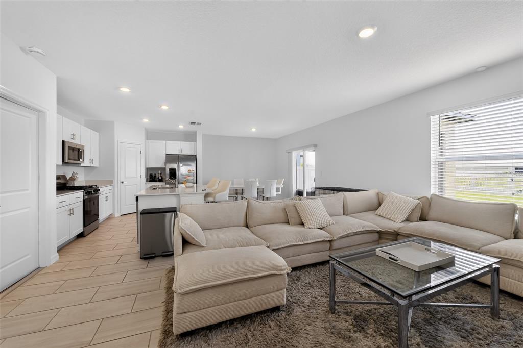 An open-concept living room and kitchen feature a large sectional sofa and tile flooring — 13065 EMPRESS JEWEL TRAIL, PARRISH, FL