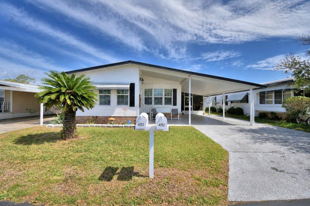 A white manufactured home features a carport, a palm tree, and two mailboxes in front — 4253 CEDARWOOD STREET, WINTER HAVEN, FL