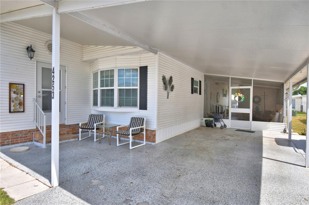 A white mobile home exterior features a covered carport, a bay window, and a patio — 4253 CEDARWOOD STREET, WINTER HAVEN, FL