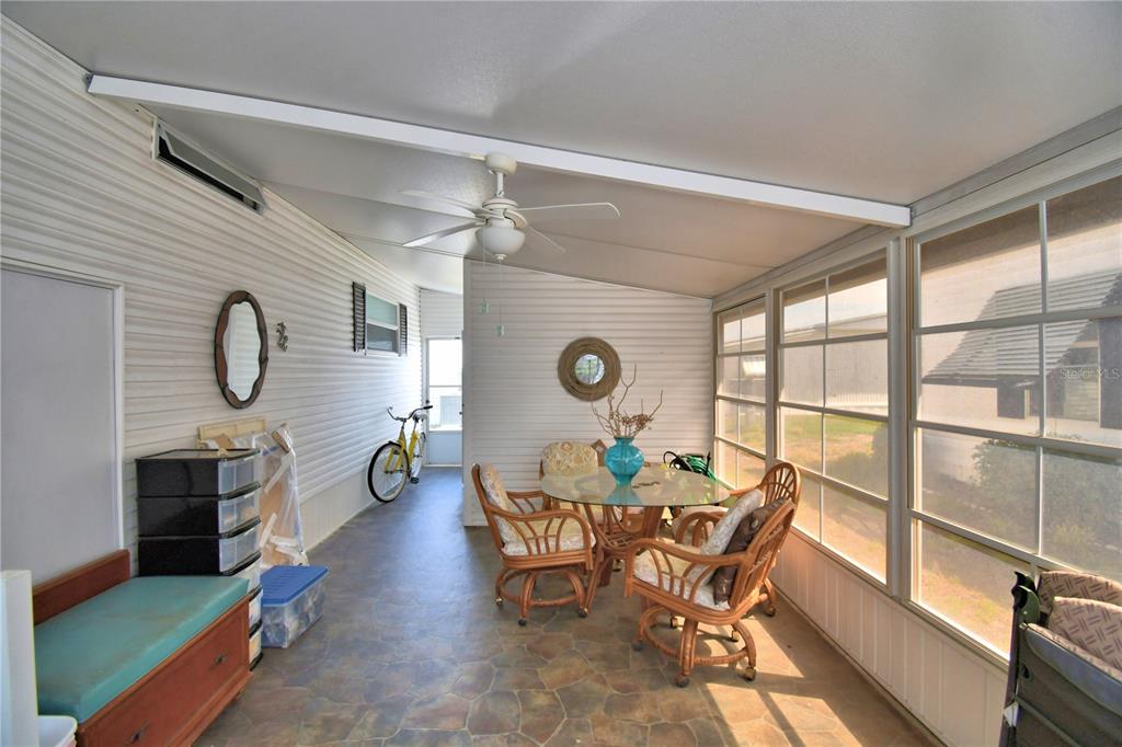 A sunroom features a dining set, a ceiling fan, and a yellow bicycle — 4253 CEDARWOOD STREET, WINTER HAVEN, FL