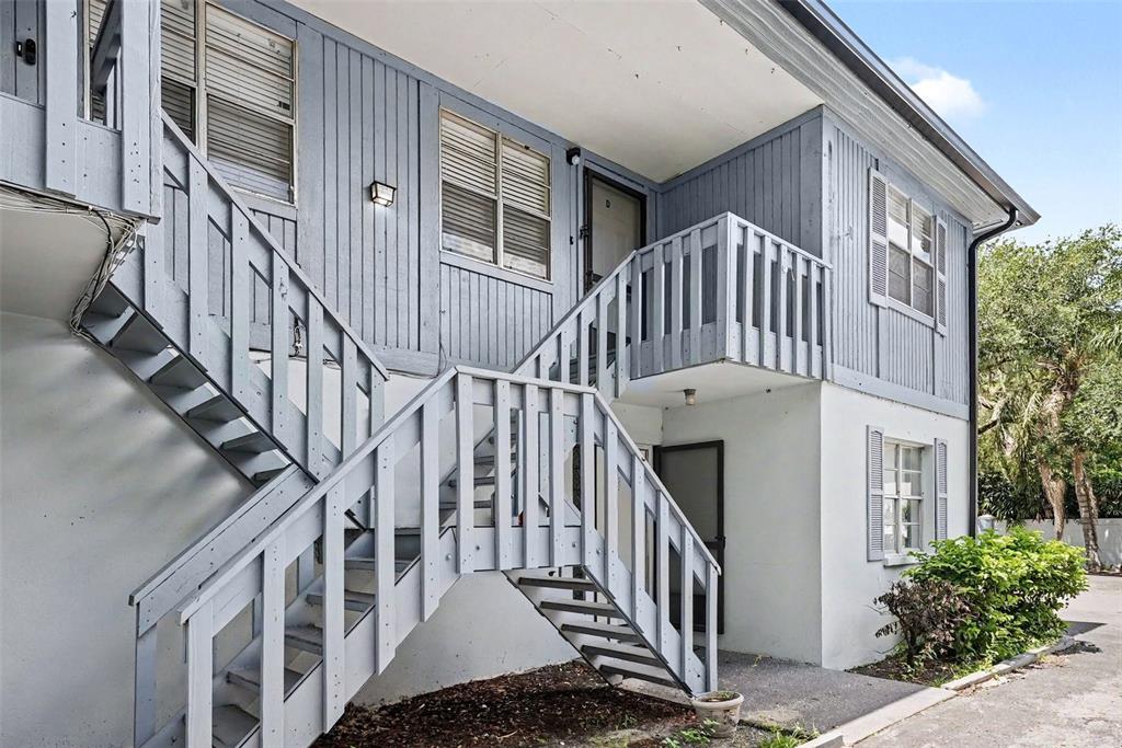 A two-story apartment building exterior features light blue vertical siding and an outdoor staircase — 9208 N CONNECHUSETT ROAD UNIT D, TAMPA, FL