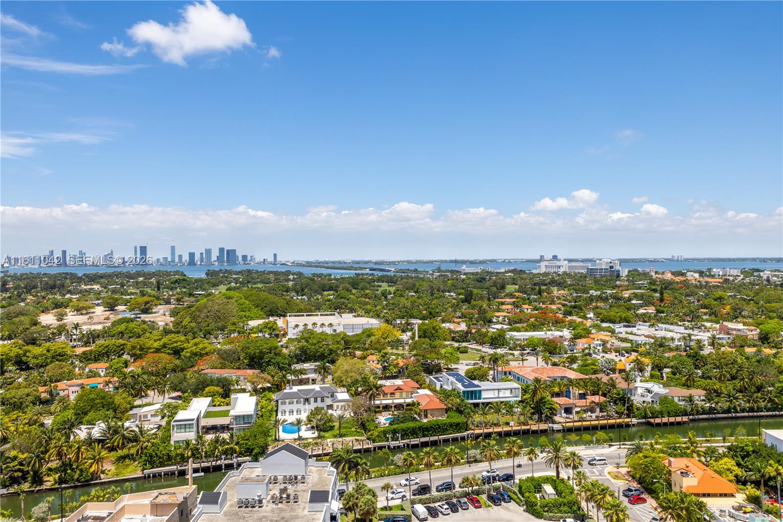 An elevated outdoor view shows a suburban neighborhood with houses, canals, and a distant skyline — 2655 Collins Ave # 2302, Miami Beach FL 33140, MIAMI BEACH, FL