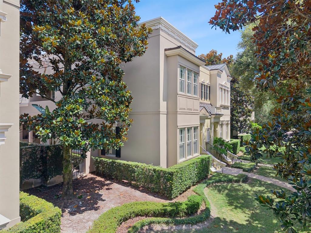 A multi-story beige townhouse exterior features manicured hedges and mature trees in the front yard — 1138 S PENNSYLVANIA AVENUE, WINTER PARK, FL