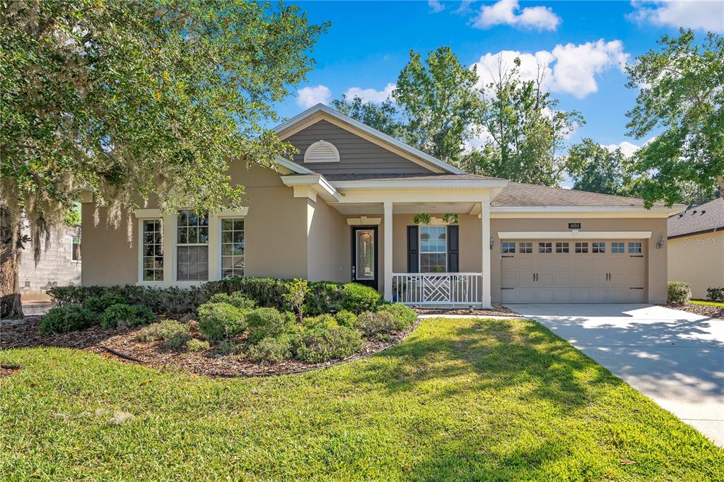 A single-story house with a tan exterior, a front porch, and a two-car garage — 4684 SOUTHERN VALLEY LOOP, BROOKSVILLE, FL