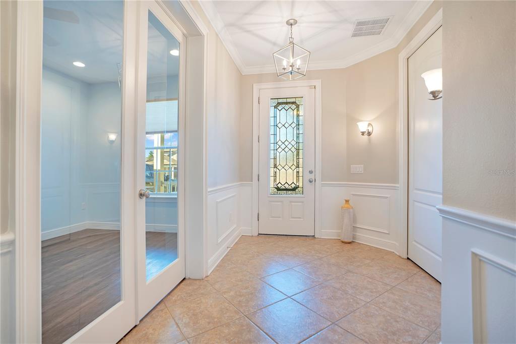 A tiled entryway features white wainscoting, a glass-paneled front door, and French doors to a room — 4684 SOUTHERN VALLEY LOOP, BROOKSVILLE, FL