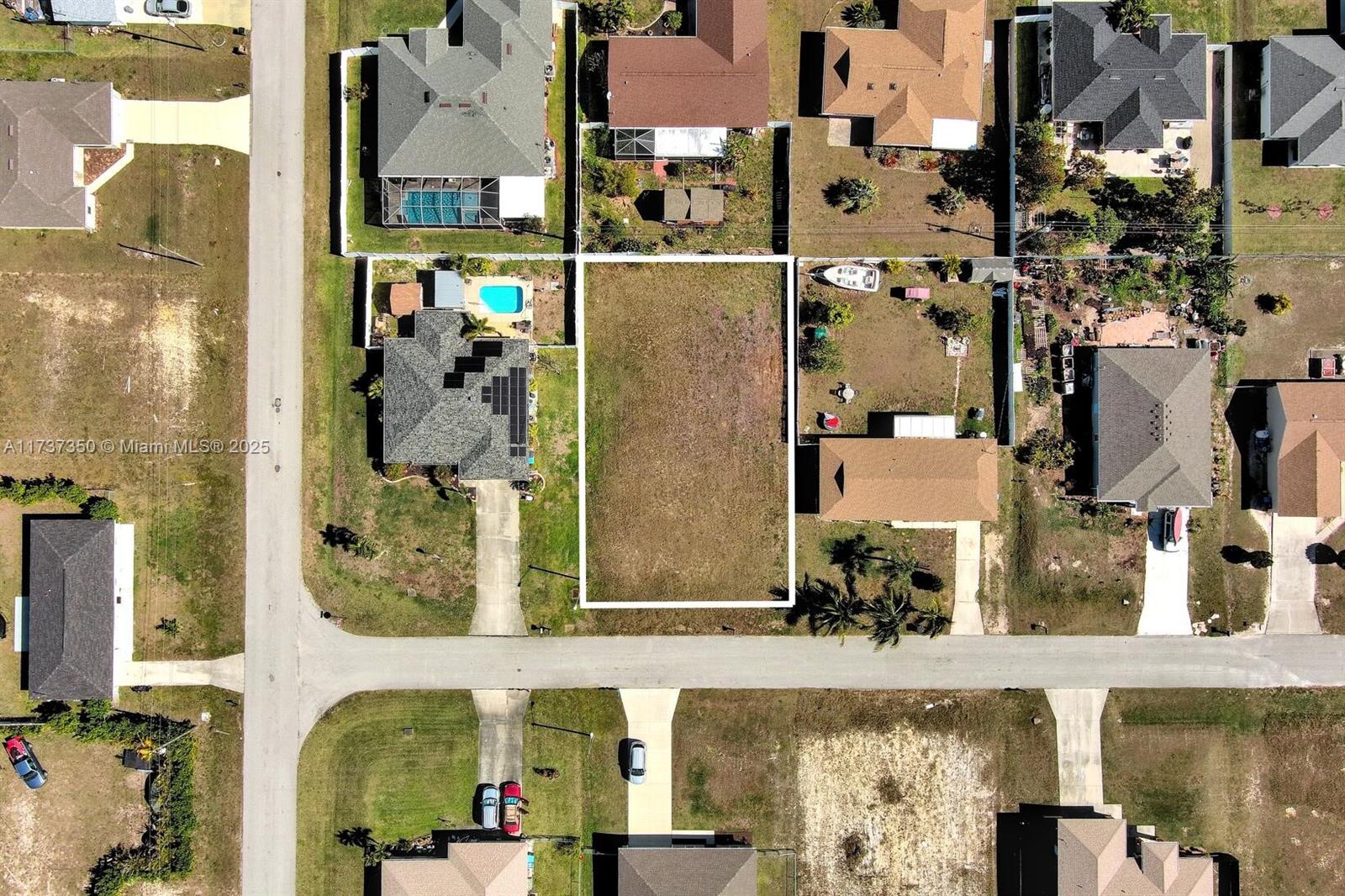 An aerial view shows a vacant rectangular residential lot situated between two existing houses — 2013 NE 18th Ave, Cape Coral FL 33909, CAPE CORAL, FL