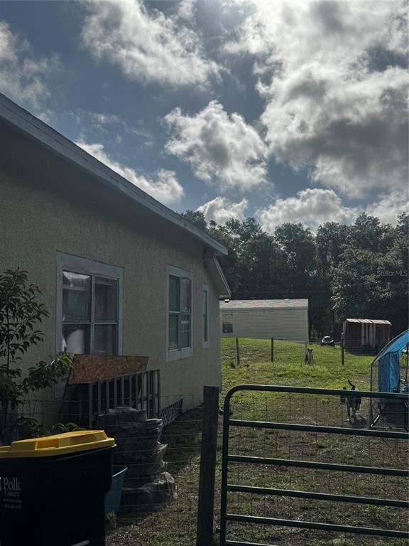 A side view of a light-colored house with a yard, fence, and a storage shed — 7001 COLUMBIA DRIVE, MULBERRY, FL
