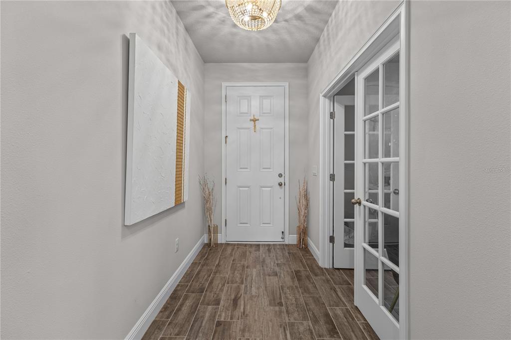 A foyer with wood-look tile flooring, a white front door, and a glass-paned French door — 5429 HOPE SOUND CIRCLE, SARASOTA, FL