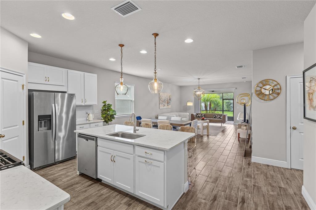 A kitchen with a white island and stainless steel appliances opens into a living area — 5429 HOPE SOUND CIRCLE, SARASOTA, FL