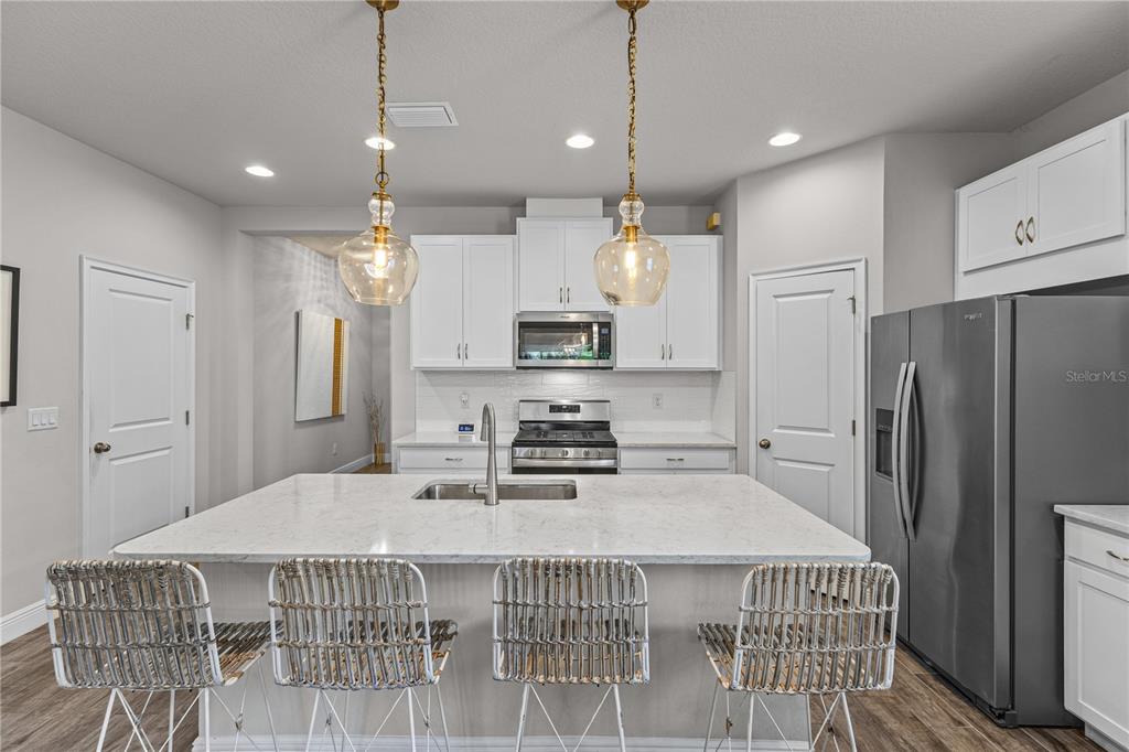 A modern kitchen features a white quartz island, pendant lights, and stainless steel appliances — 5429 HOPE SOUND CIRCLE, SARASOTA, FL