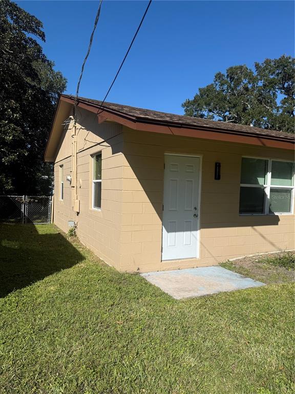 A tan concrete block building features a white door, brown trim, and a shingled roof — 305 ANN STREET, EDGEWATER, FL