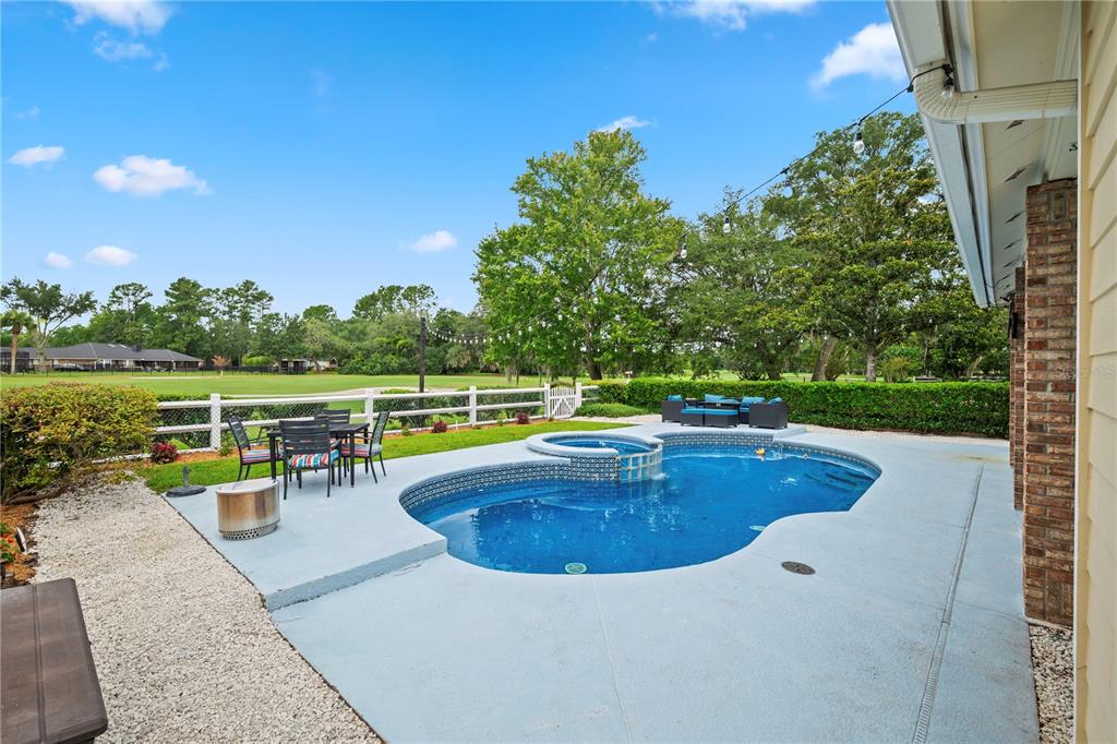 A backyard features a swimming pool, a hot tub, patio furniture, and a white fence — 3729 CONSTANCIA DRIVE, GREEN COVE SPRINGS, FL