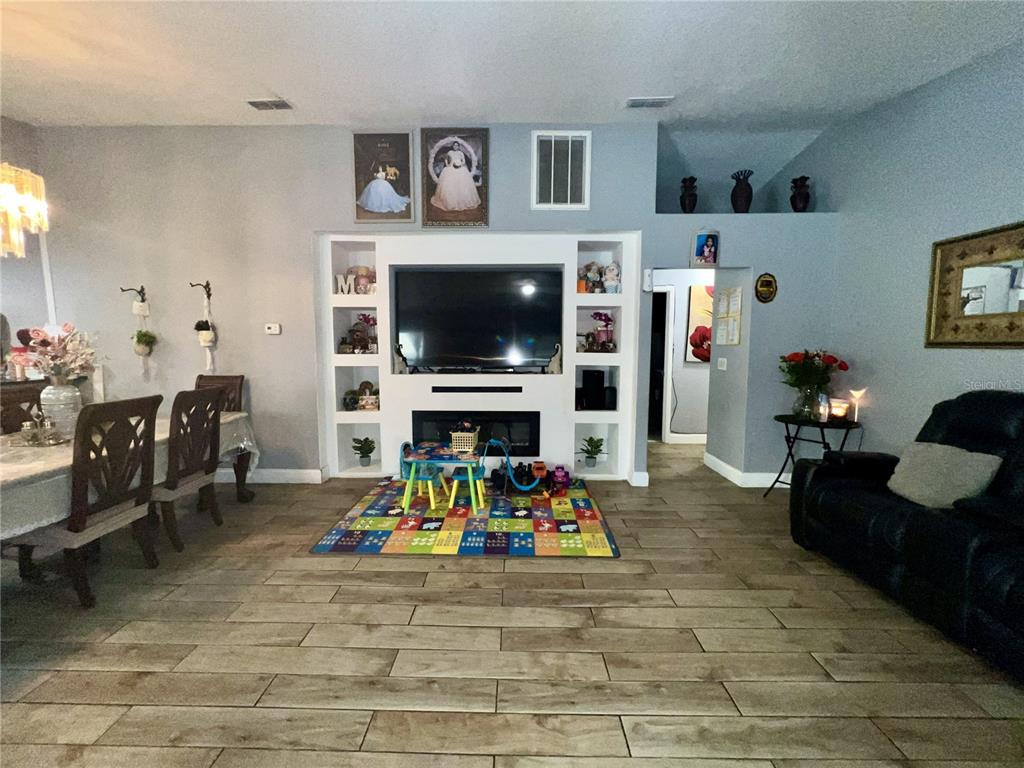 A living room features a built-in media center with a fireplace, tile flooring, and dining area — 10804 N MYRTLE STREET, TAMPA, FL