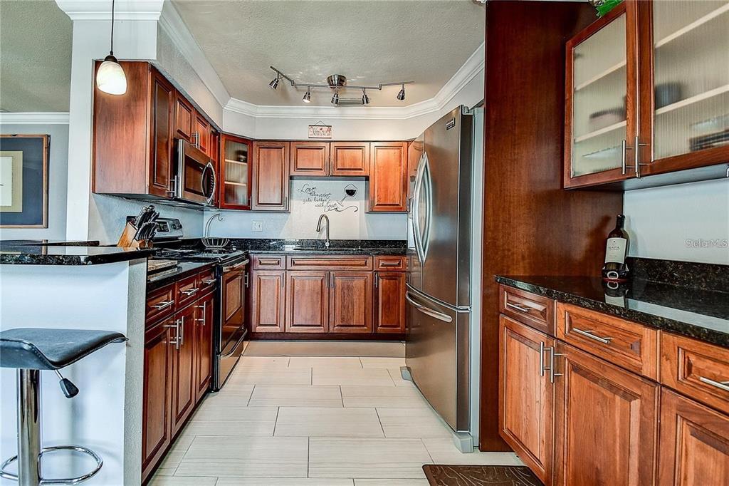 A kitchen with dark wood cabinets, stainless steel appliances, and black granite countertops — 5111 COQUINA KEY DRIVE SE UNIT C, ST PETERSBURG, FL