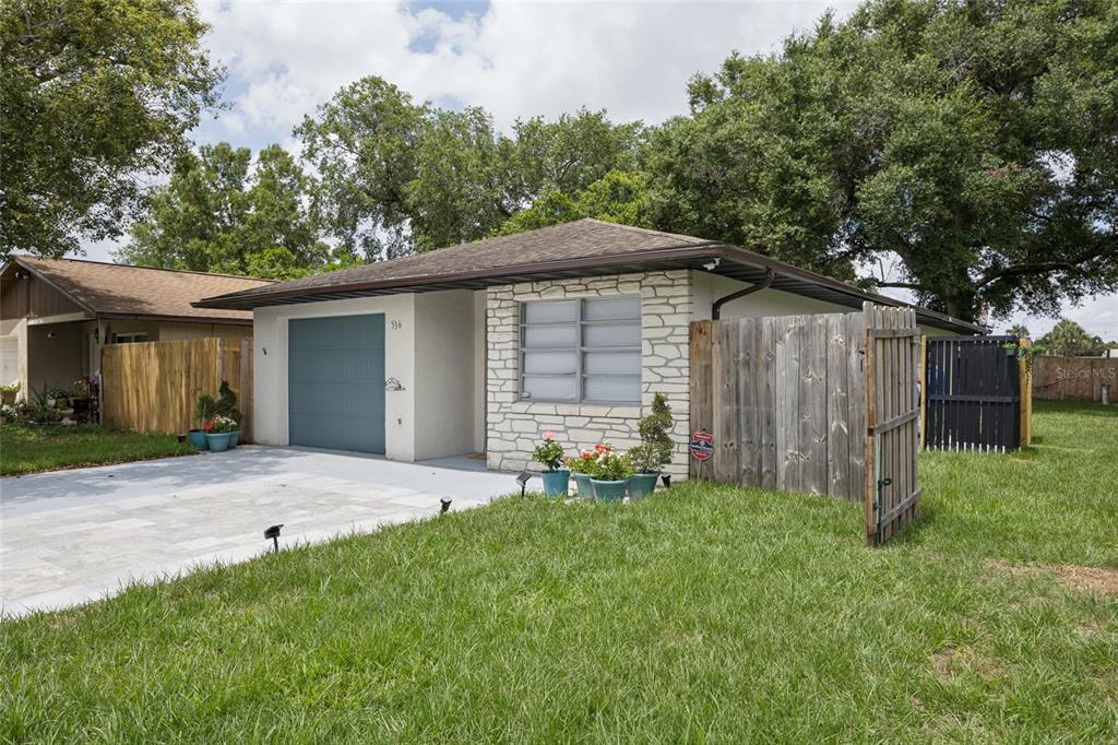 A single-story house features a blue garage door, stone facade, and a wooden privacy fence — 536 HIBISCUS WAY UNIT 7B, ORLANDO, FL