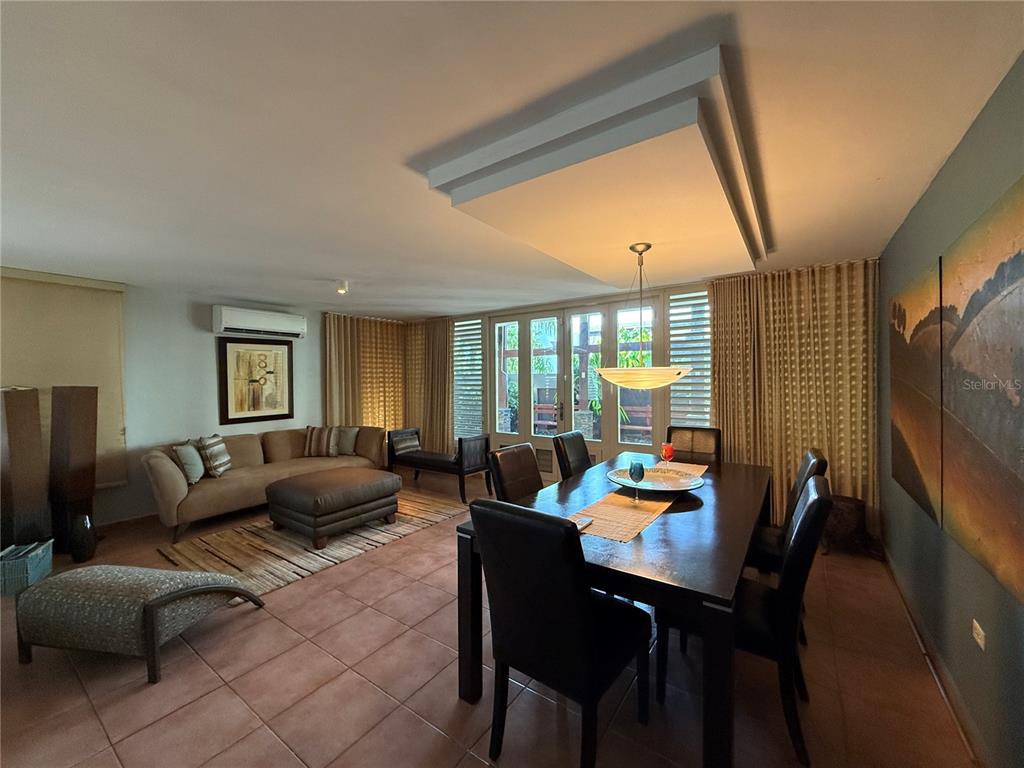 An open-concept living and dining room features tile flooring, a tray ceiling, and large windows — . TOPACIO STREET UNIT F-22, DORADO, PR