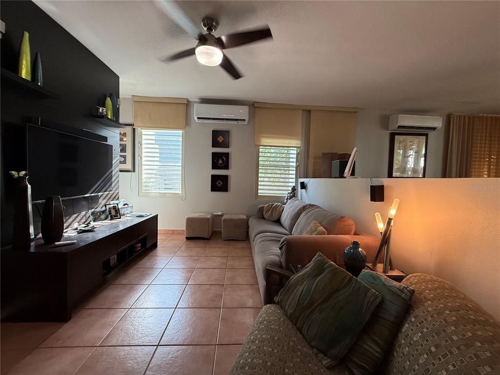 A living room features tile flooring, a large television, a sofa, and two wall-mounted air conditioners — . TOPACIO STREET UNIT F-22, DORADO, PR