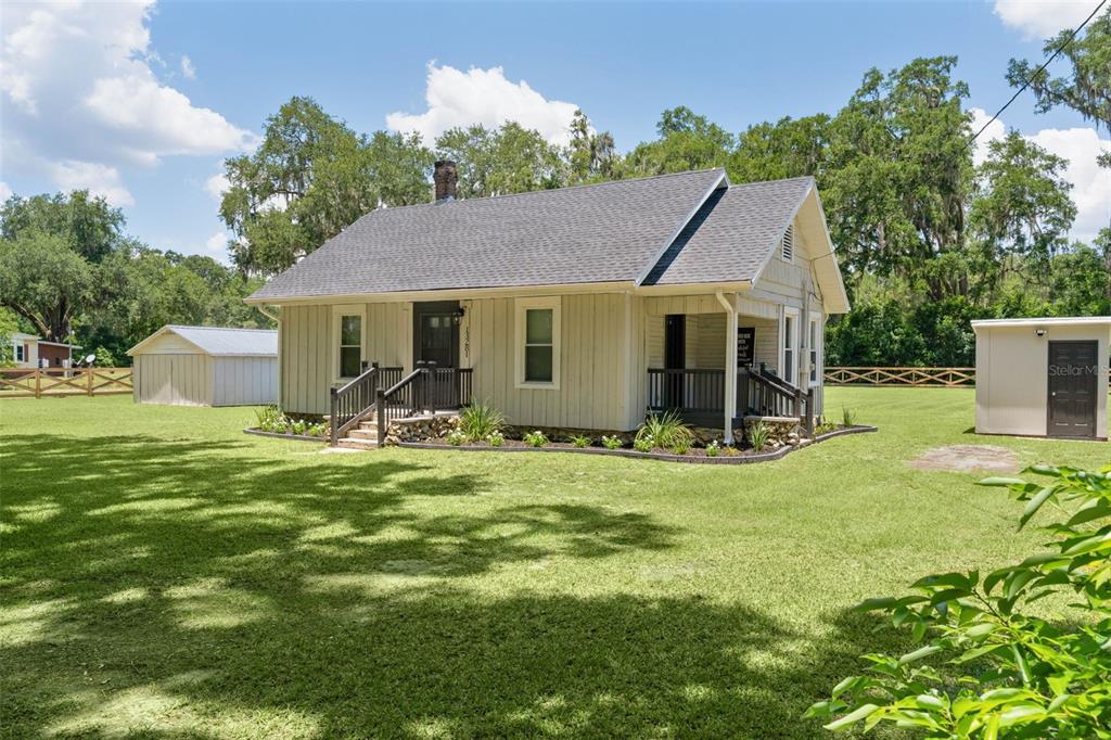 A light-colored, single-story house with a dark roof sits on a large, grassy lot — 13281 SE 122ND PLACE, OCKLAWAHA, FL