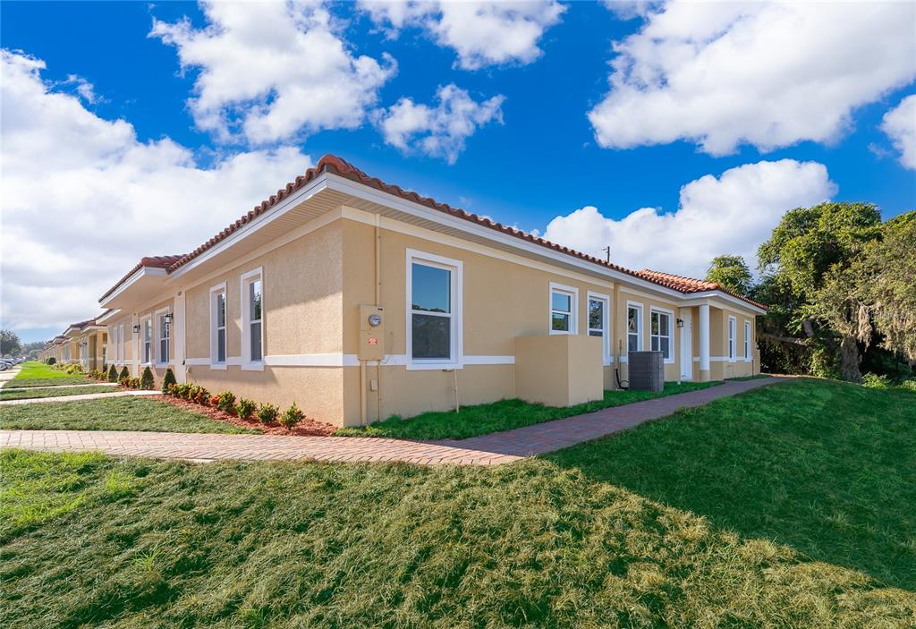 A side view of a tan, single-story stucco building with a red tile roof — 1659 CUMIN DRIVE, KISSIMMEE, FL