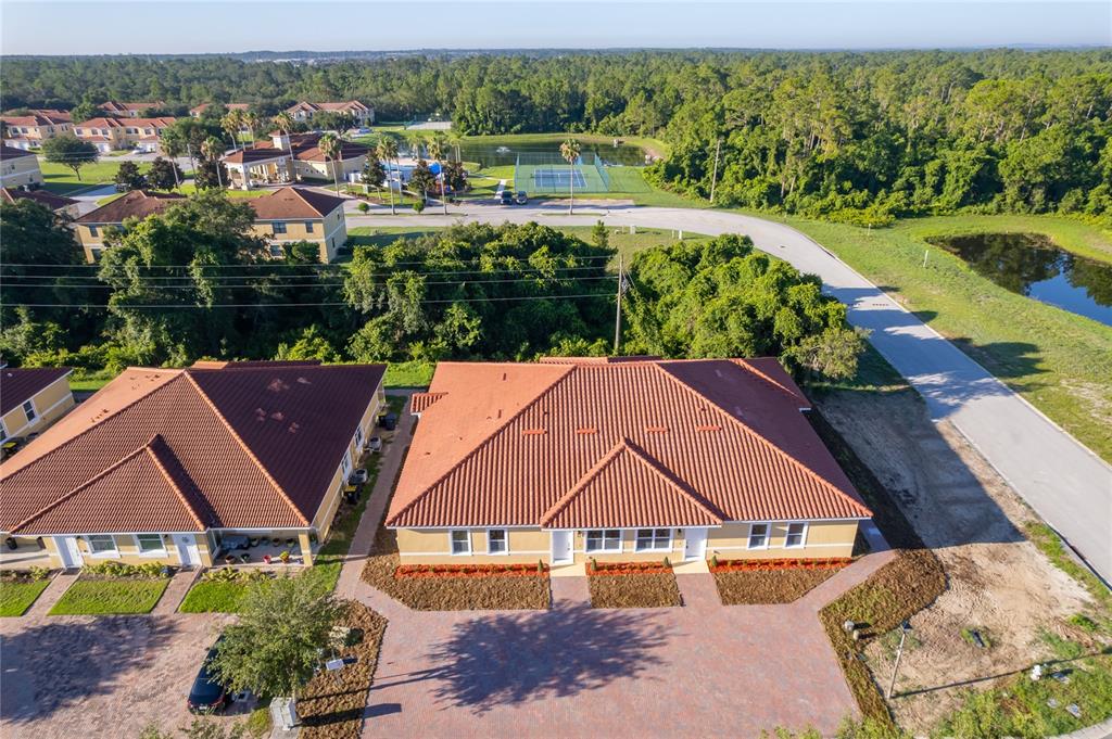 An aerial view shows two adjacent residential buildings with red tile roofs and brick driveways — 1659 CUMIN DRIVE, KISSIMMEE, FL