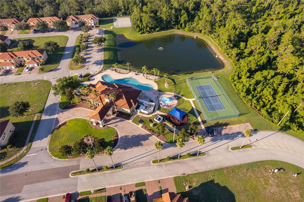 An aerial view shows a community clubhouse with a pool, tennis court, and pond — 1659 CUMIN DRIVE, KISSIMMEE, FL