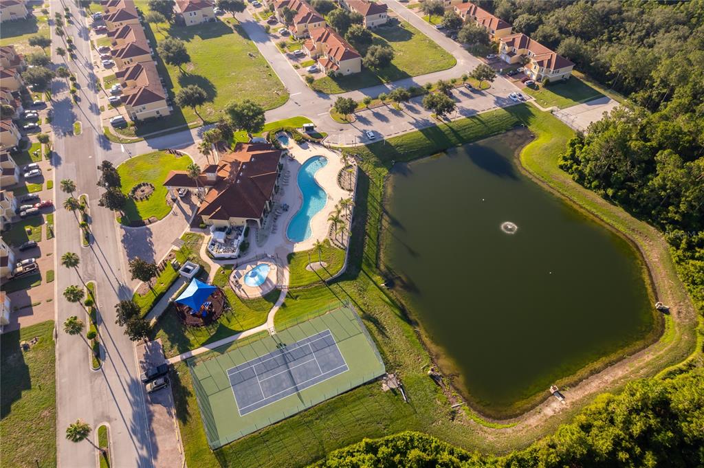 An aerial view shows a community clubhouse with a pool, tennis court, and a pond — 1659 CUMIN DRIVE, KISSIMMEE, FL
