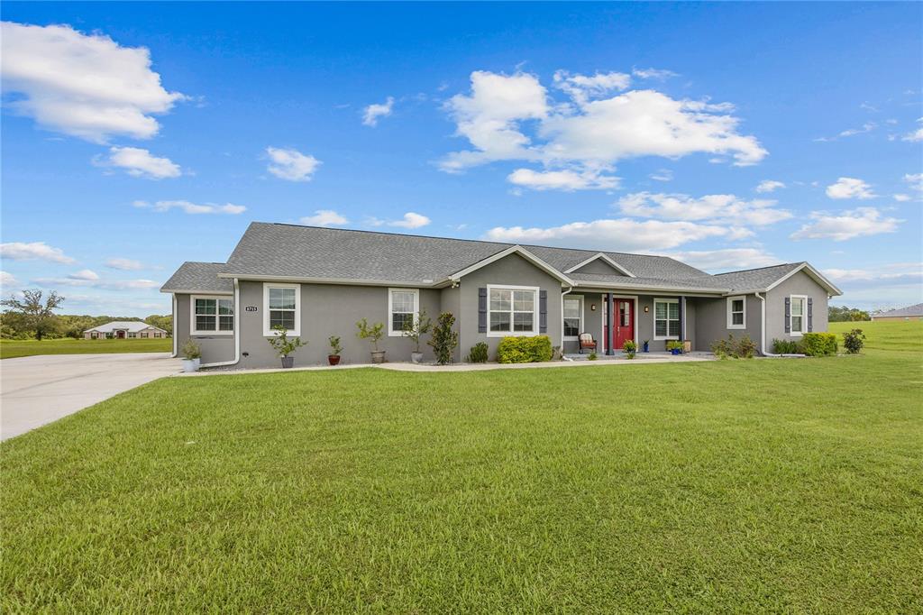 A single-story gray house with a red front door sits on a large grassy lot — 8715 NW 18TH CIRCLE, OCALA, FL