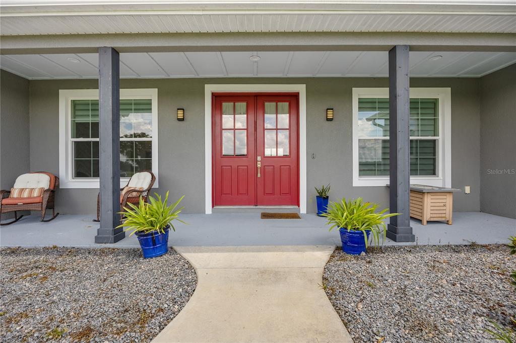 A front porch features a red double door, two dark columns, and potted plants — 8715 NW 18TH CIRCLE, OCALA, FL