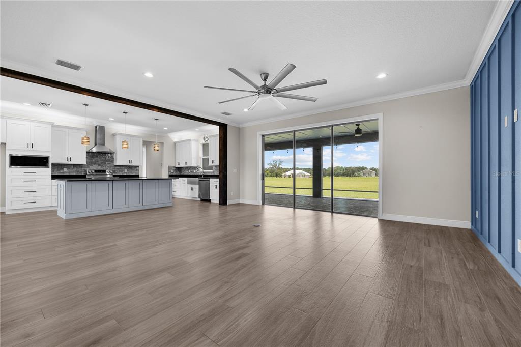 An open-concept living area with wood-look tile flooring, a large kitchen, and sliding glass doors — 8715 NW 18TH CIRCLE, OCALA, FL