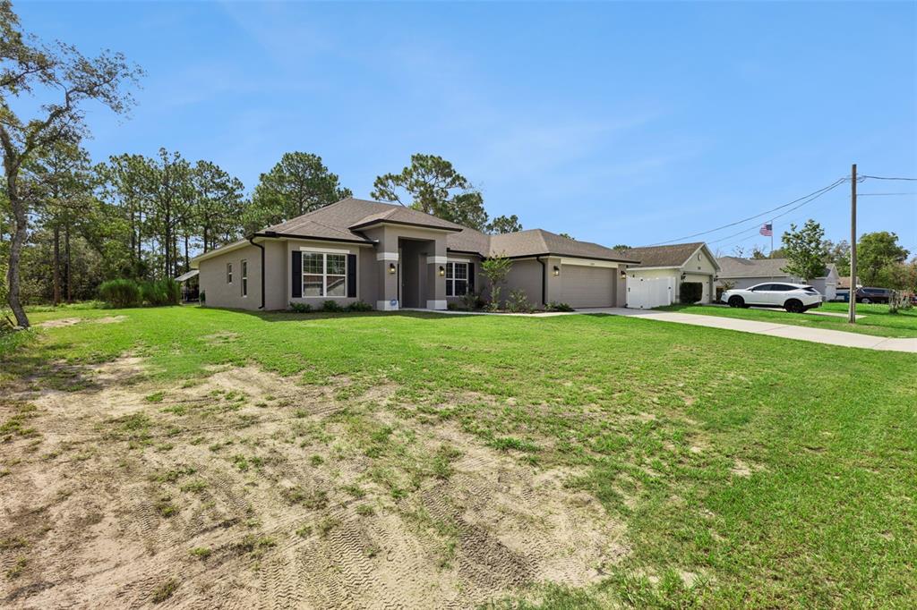 A single-story house with a gray exterior, a two-car garage, and a large front lawn — 11268 KODIAK WREN ROAD, WEEKI WACHEE, FL