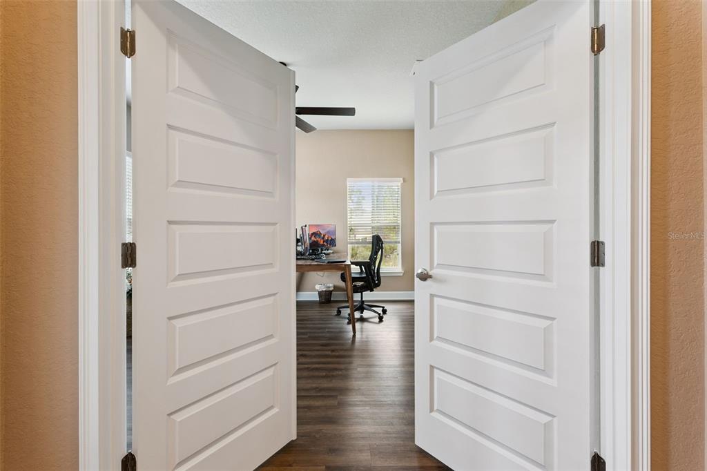 A view through double doors into a home office with wood-look flooring and a window — 11268 KODIAK WREN ROAD, WEEKI WACHEE, FL