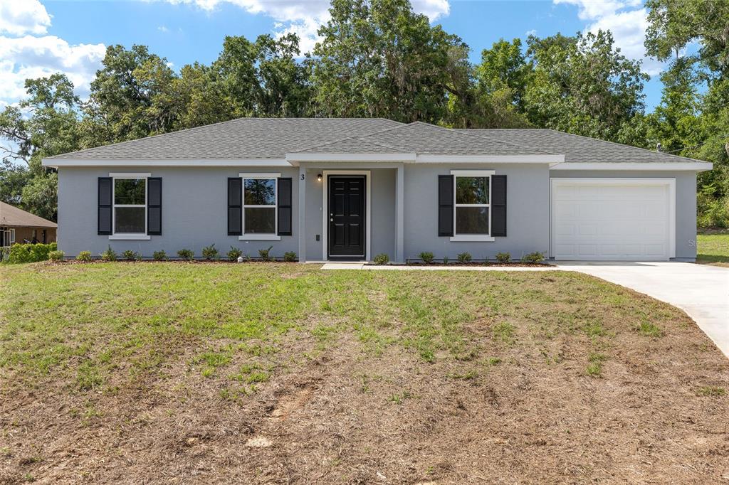 A single-story gray house with black shutters, a black front door, and a white garage — 3 JUNIPER PASS PLACE, OCALA, FL