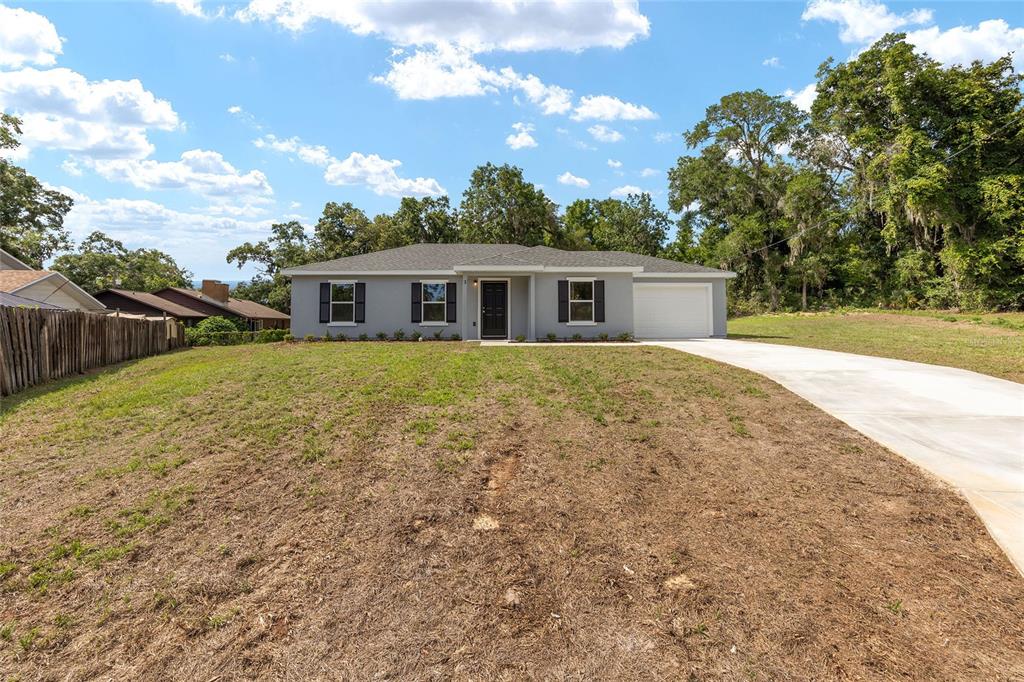 A single-story gray house with a white garage and a large, unlandscaped front yard — 3 JUNIPER PASS PLACE, OCALA, FL