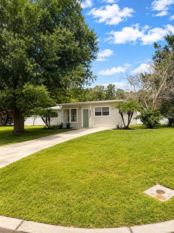 A single-story house with light-colored siding, a green front door, and a concrete driveway — 1725 PARK DRIVE, LAKELAND, FL