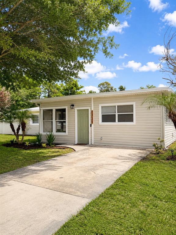 A single-story house with light-colored siding, a green front door, and a concrete driveway — 1725 PARK DRIVE, LAKELAND, FL
