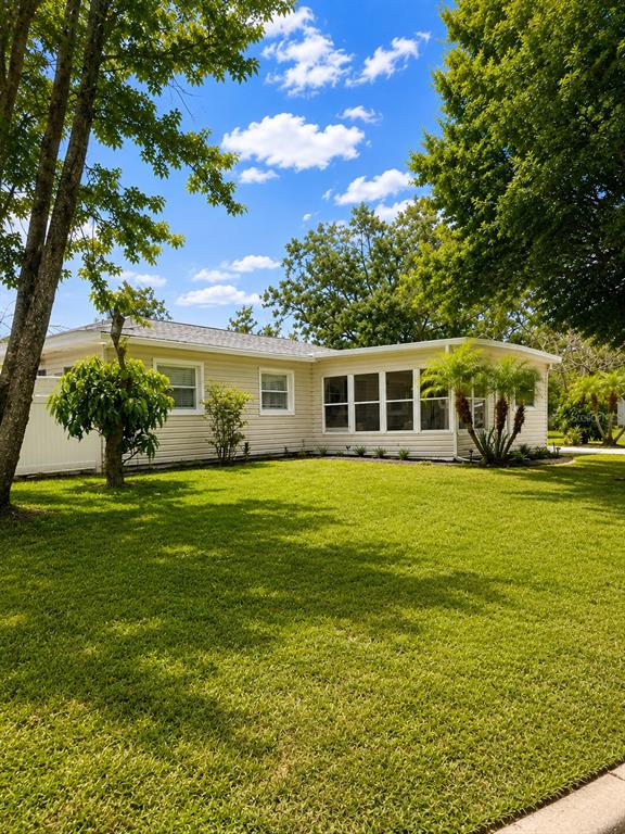 A single-story house with light-colored siding and a large green lawn under a blue sky — 1725 PARK DRIVE, LAKELAND, FL
