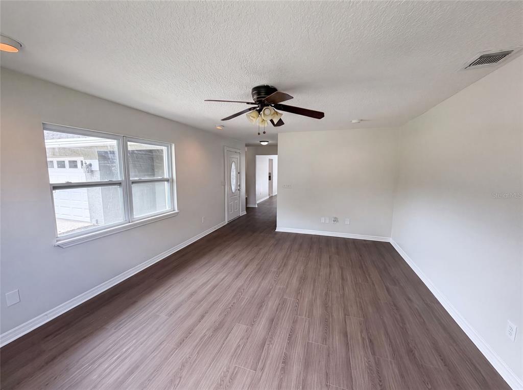 A living room features light gray walls, wood-look flooring, a ceiling fan, and a front door — 963 SEQUOIA DRIVE, WINTER SPRINGS, FL