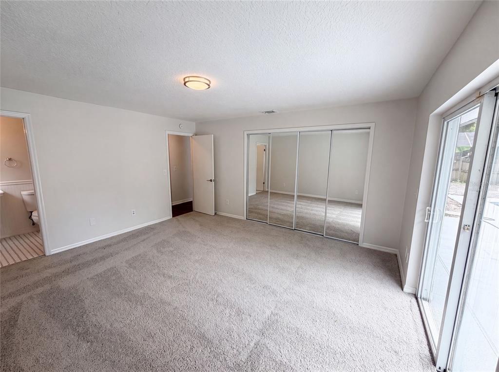 A bedroom with gray carpet, mirrored closet doors, a ceiling light, and an attached bathroom — 963 SEQUOIA DRIVE, WINTER SPRINGS, FL