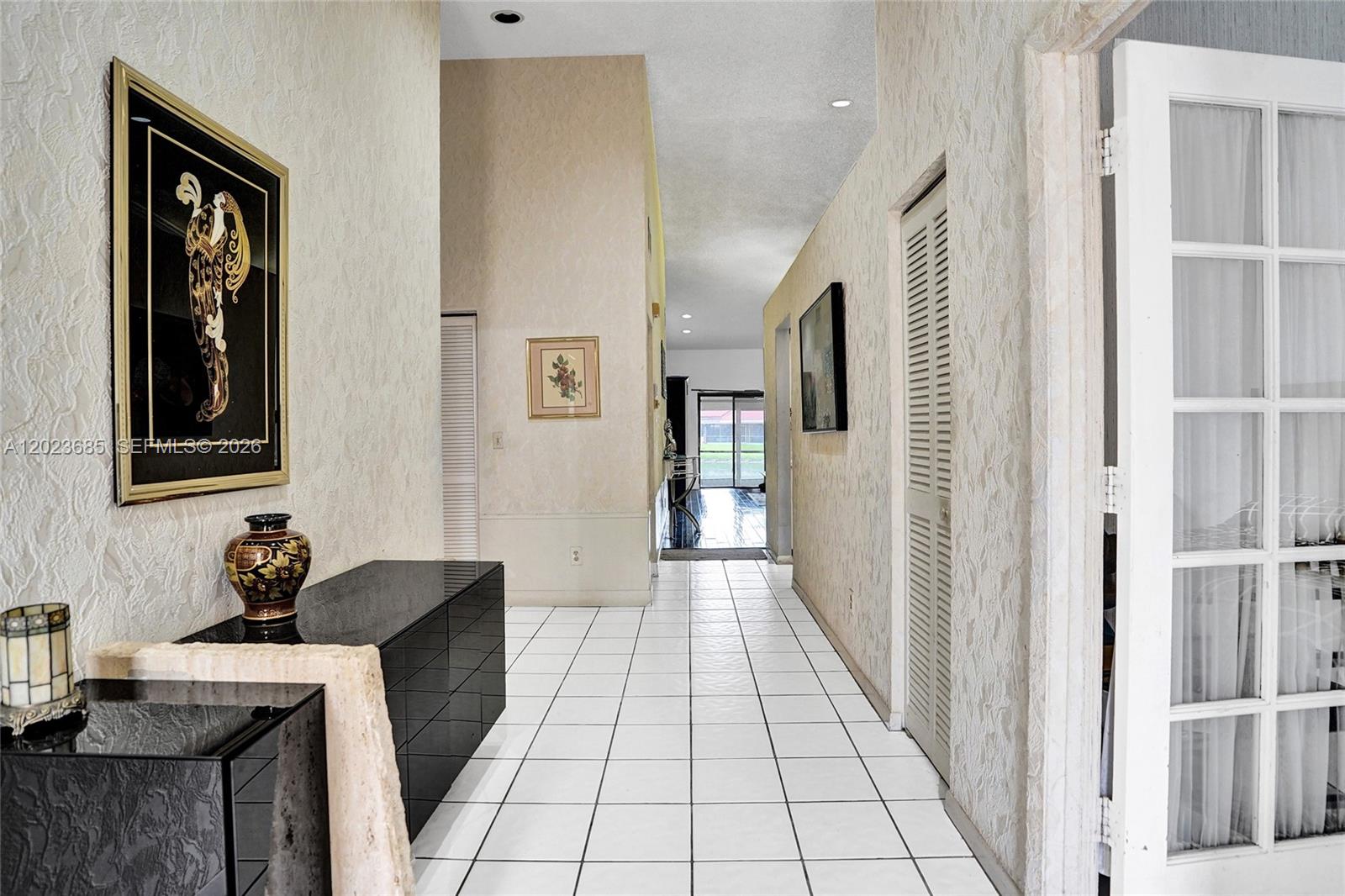 A tiled hallway leads toward a glass door with views of an outdoor patio area — 3273 W Inverrary Blvd W, Lauderhill FL 33319, LAUDERHILL, FL