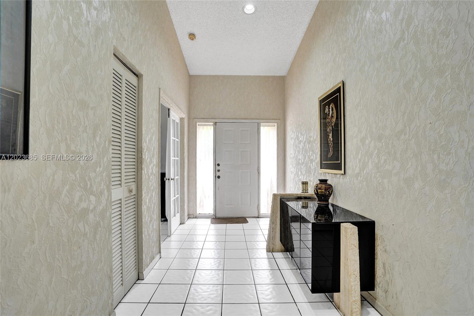 A tiled foyer features a white front door, textured walls, and a black console table — 3273 W Inverrary Blvd W, Lauderhill FL 33319, LAUDERHILL, FL