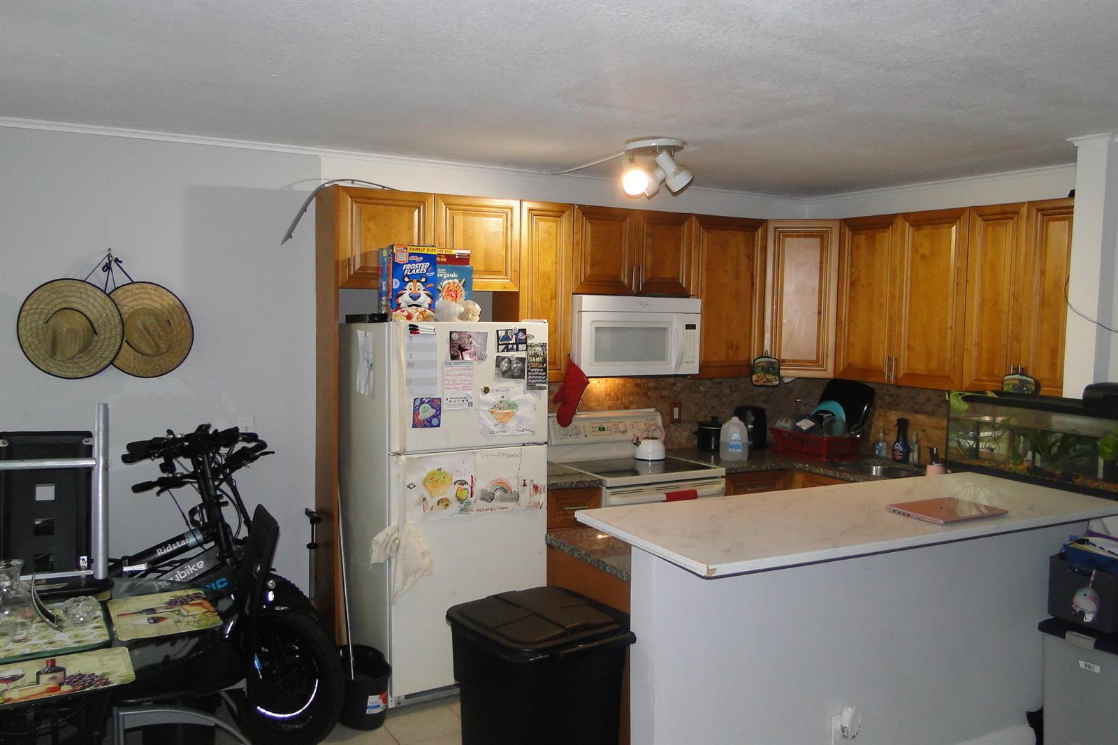 A kitchen features wood cabinets, a white refrigerator, a microwave, and a breakfast bar counter — 1829 N A Street # 32, FL 33460, FL