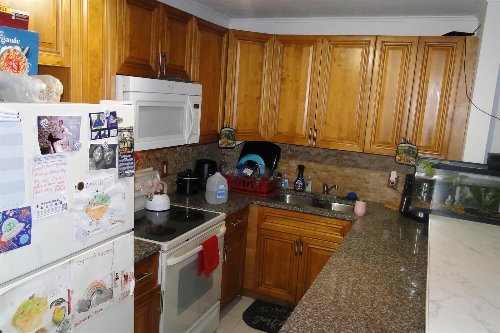 A kitchen features wood cabinets, granite countertops, a white stove, and a double-basin sink — 1829 N A Street # 32, FL 33460, FL