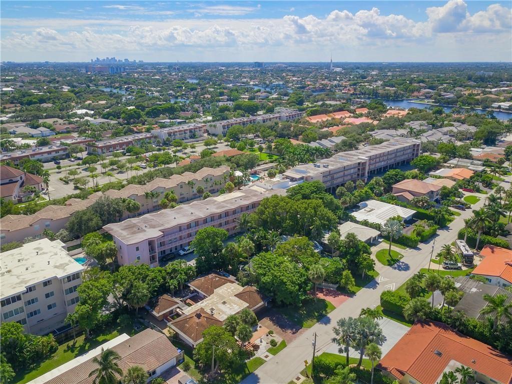 An aerial view shows multi-story apartment buildings surrounded by lush trees and suburban residential homes — 1967 S Ocean Boulevard # D, Pompano Beach FL 33062, POMPANO BEACH, FL